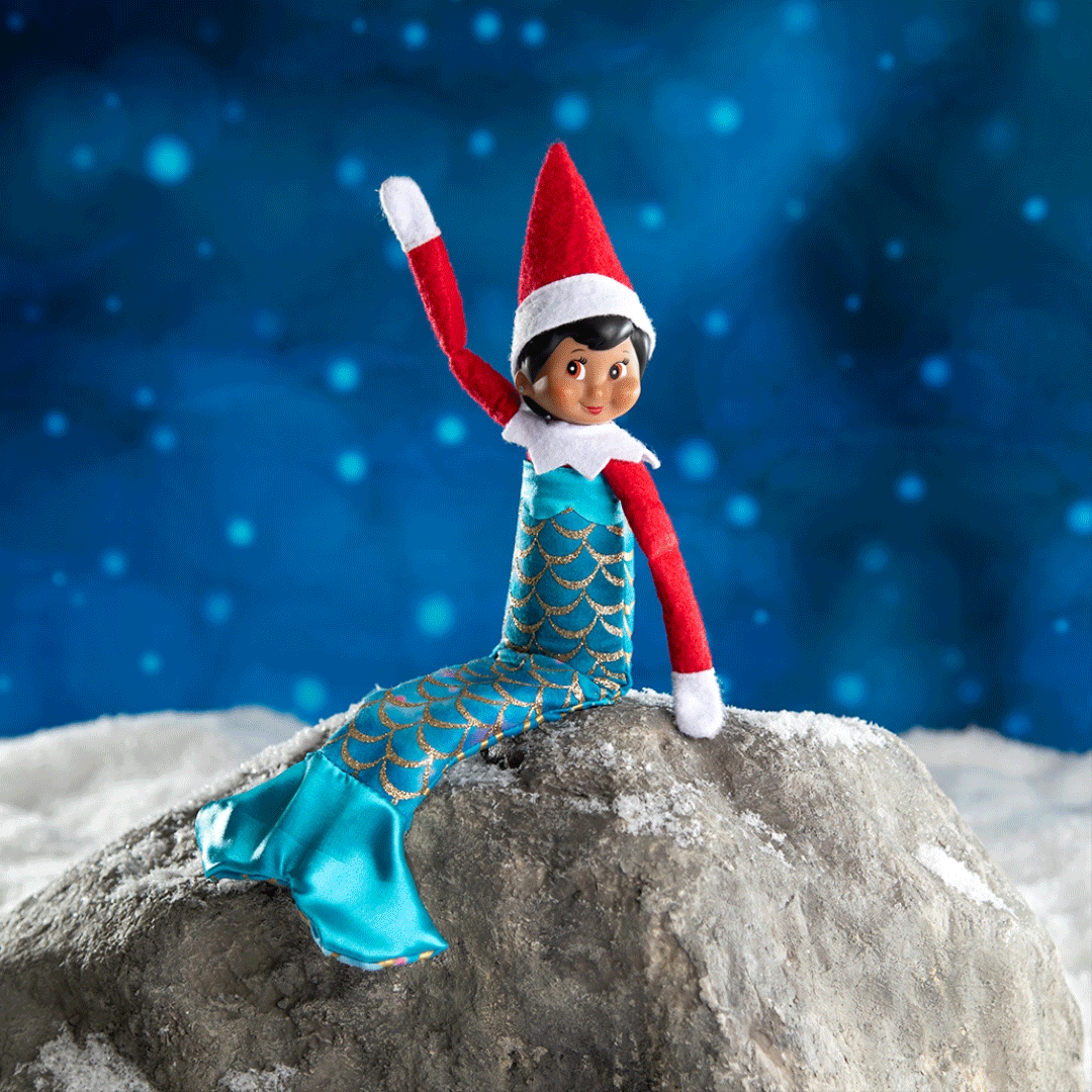 Elf in mermaid costume sitting and waving on rock