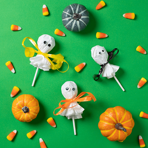 Ghost pops on green background with candy corn