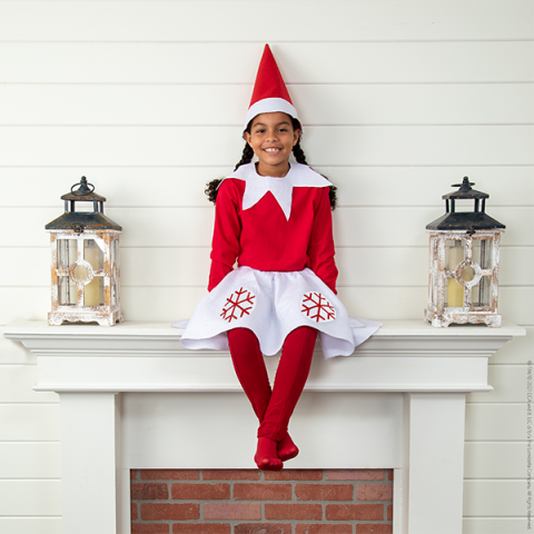 Girl in Scout Elf costume (with skirt) sitting on mantle