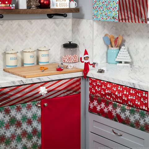 Elf with Christmas paper wrapped kitchen cabinets and drawers 