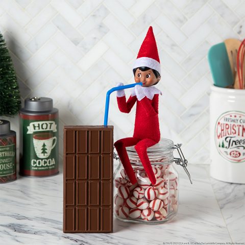 Elf 'drinking' from chocolate candy bar with a straw