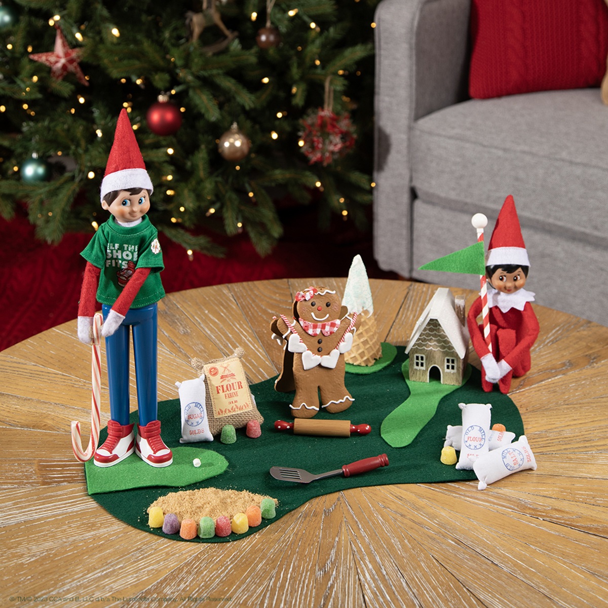 Alt text: The Elf on the Shelf and friend playing golf with a candy cane golf club.
