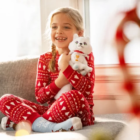 A young girl in pajamas cuddles the Elf Pets Arctic Fox plush