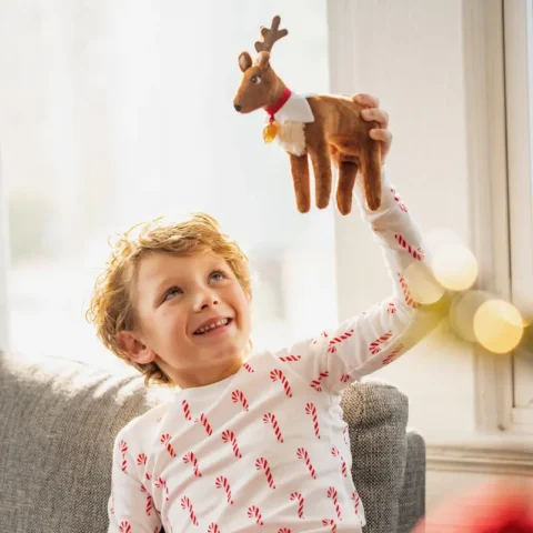 Young boy holds Elf Pets reindeer in his hand and flies it over his head
