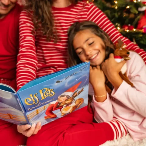 Young girl cuddles with Elf Pets Reindeer while reading the storybook