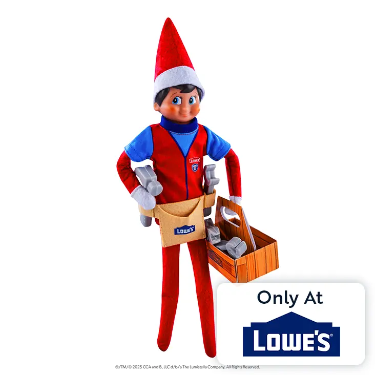 Scout Elf boy with light skin and blue eyes wearing the Polar Props™ Fix-It Fun Prop Set. He has his right hand on his hip and the toolbox carried by his left hand. On the bottom right is a graphic that says Only at Lowe's.
