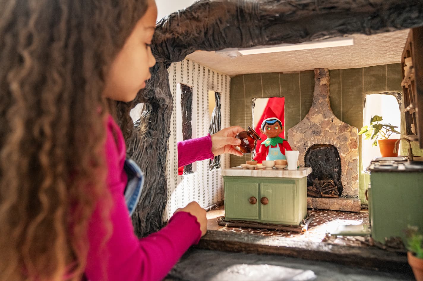 A young girl plays with an Elf Mates Chef in a woodland kitchen setting