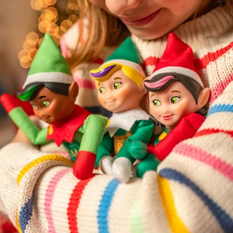 A girl hugs the Elf Mates Cobbler, Toy Maker and Girl Chef while looking down at them in her arms