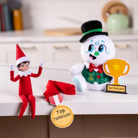 Razzle the Celebration Snowman and a girl Scout Elf show a medal and a trophy