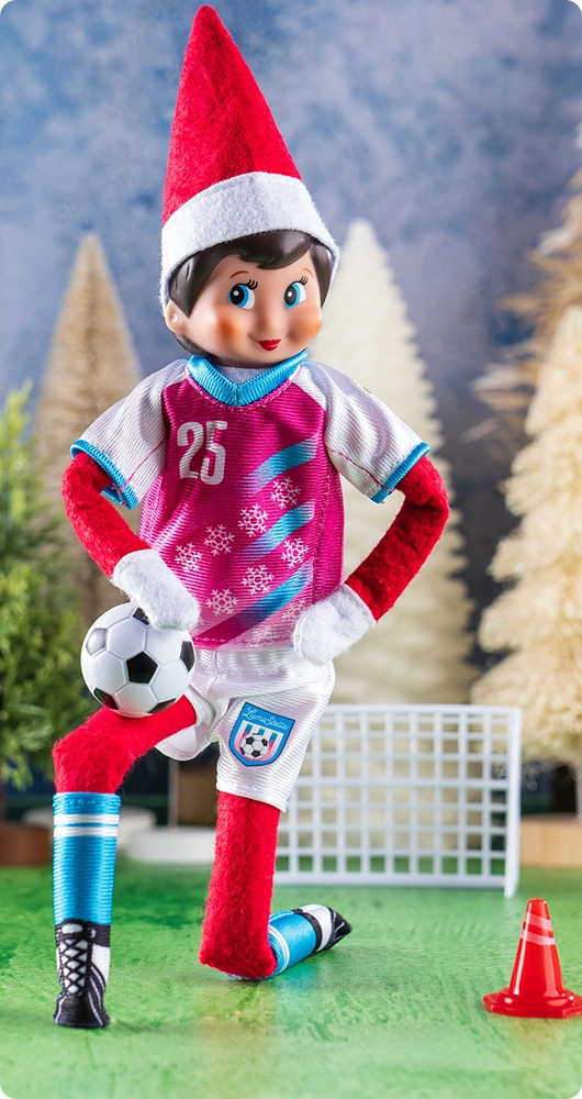 A girl Scout Elf poses wearing the Polar Props™ North Pole Pitch Kit in front of a row of conifer decor trees.
