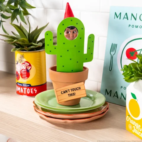 The Elf on the Shelf stands behind a printable cactus with a sign that says, "Can't Touch This!"