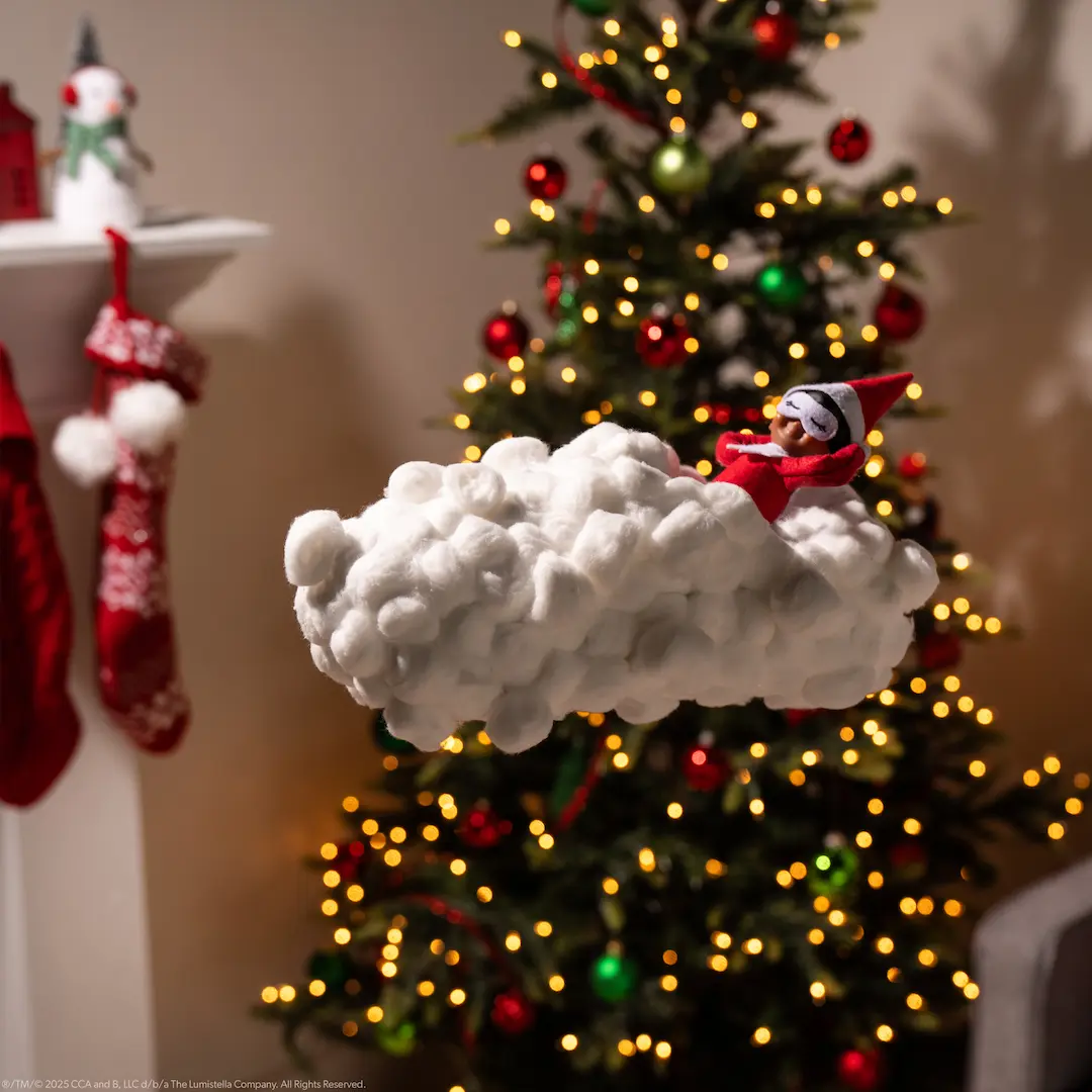 The Elf on the Shelf rests on a cloud made of cotton balls as if sleeping on air
