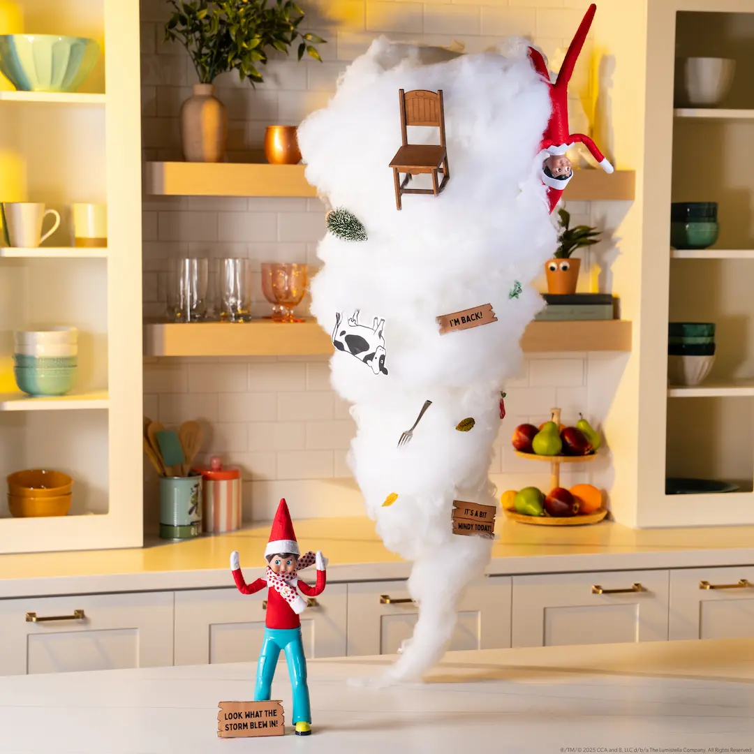 A Scout Elf stands beside a tornado made of cotton batting with a variety of items stuck to it