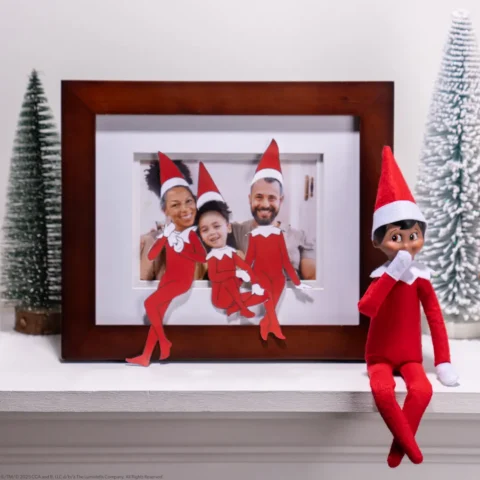 A Scout Elf sits beside a photograph of a family that has been turned into elves using printable hats and elf bodies