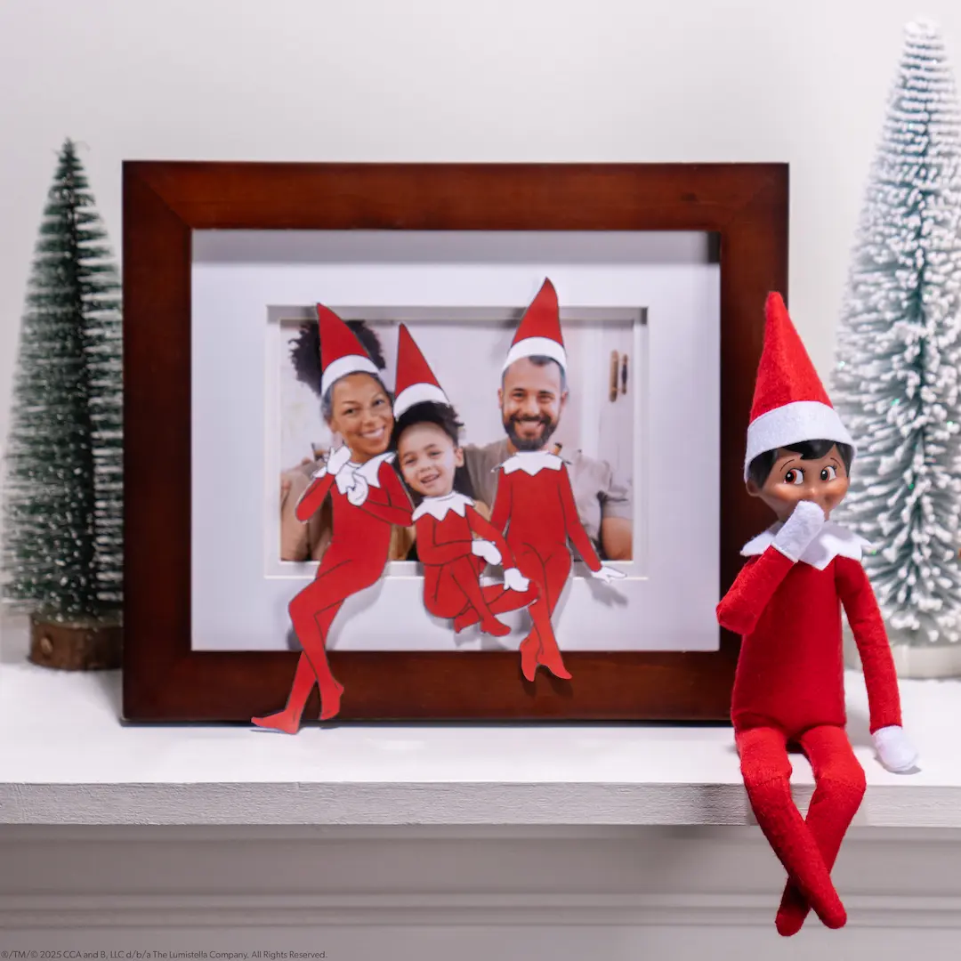 A Scout Elf sits beside a photograph of a family that has been turned into elves using printable hats and elf bodies
