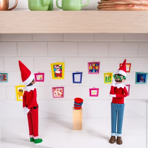 Two Scout Elves stand in front of a variety of miniature paintings as if in an art gallery