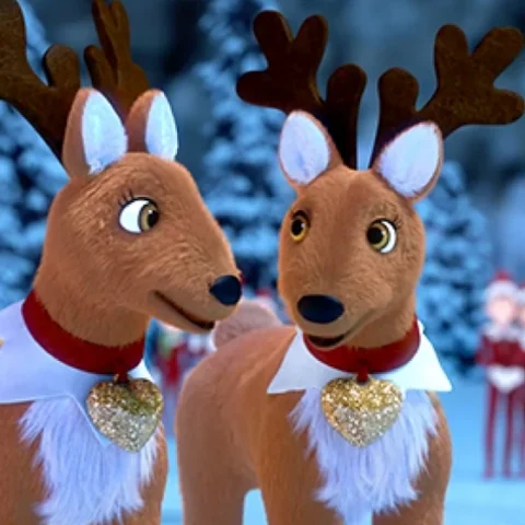 A still of a pair of Elf Pets® Reindeer looking at one another from the Scout Elves Don't Rest music video. The background is the wintery snowscape of the North Pole. A few Scout Elves are seen in the background also.