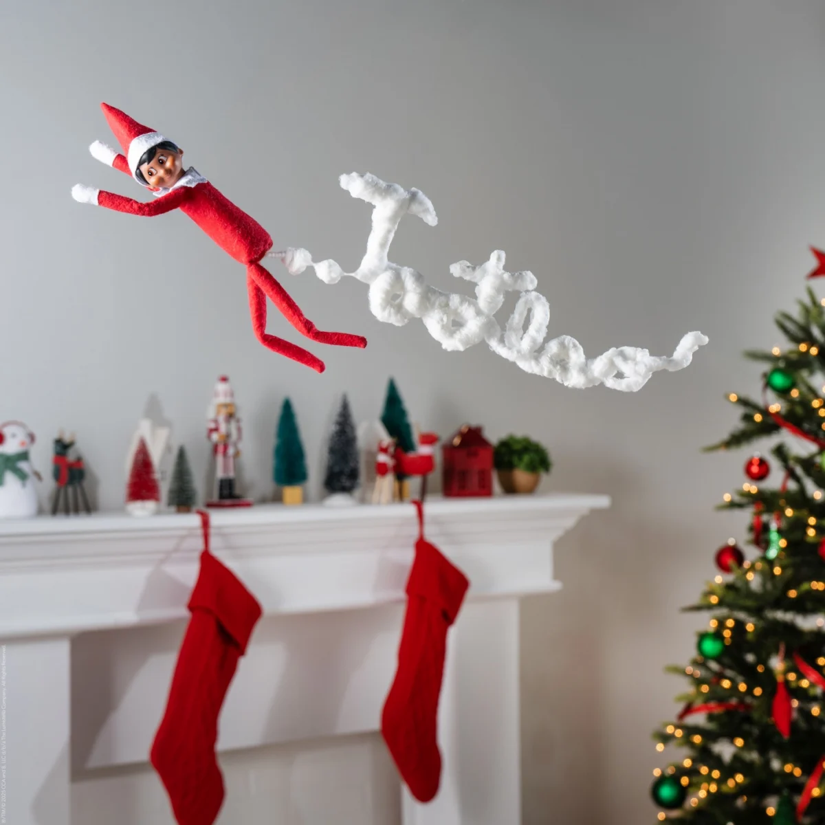 The Elf on the Shelf flies through the air as if they are passing gas in a cloud that takes the shape of the word "Tootles"