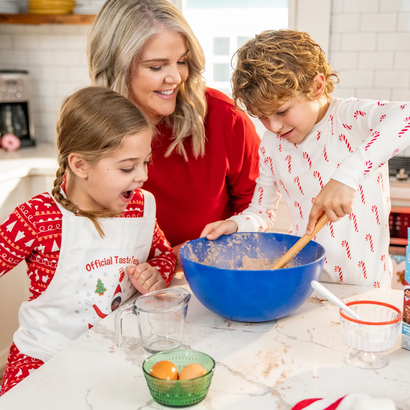 A mom and two children stir cookie batter in a blue bowl
