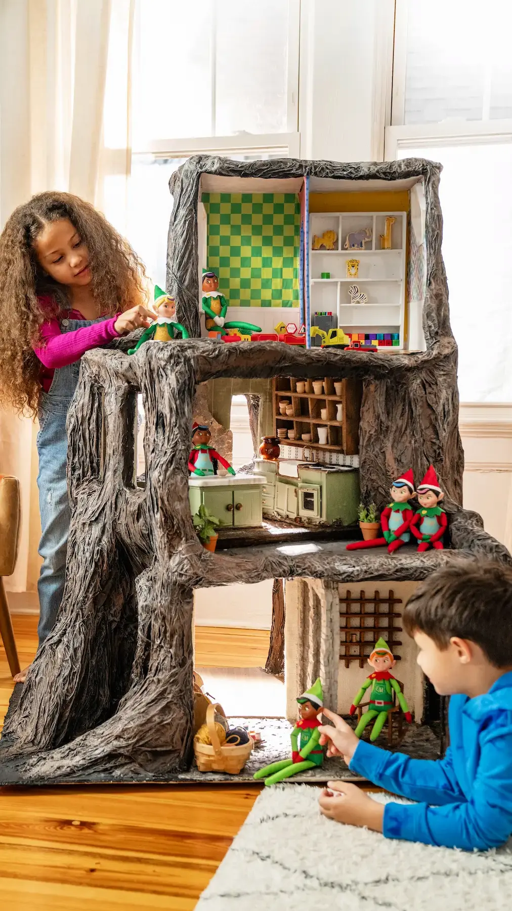 a boy and girl play with the Elf Mates in a tree-shaped dollhouse