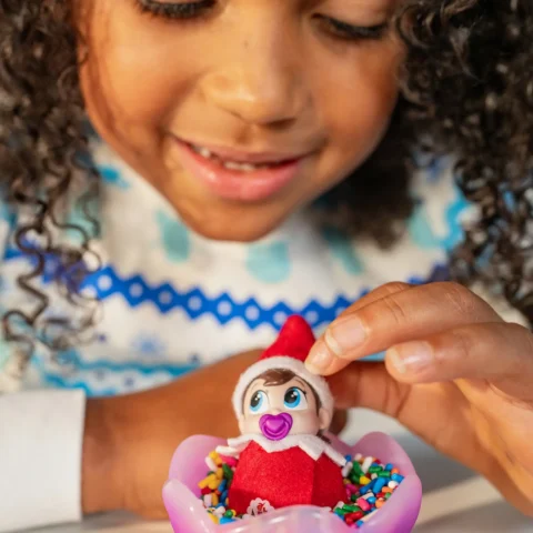 A young girl plays with a Frost Pips elf baby
