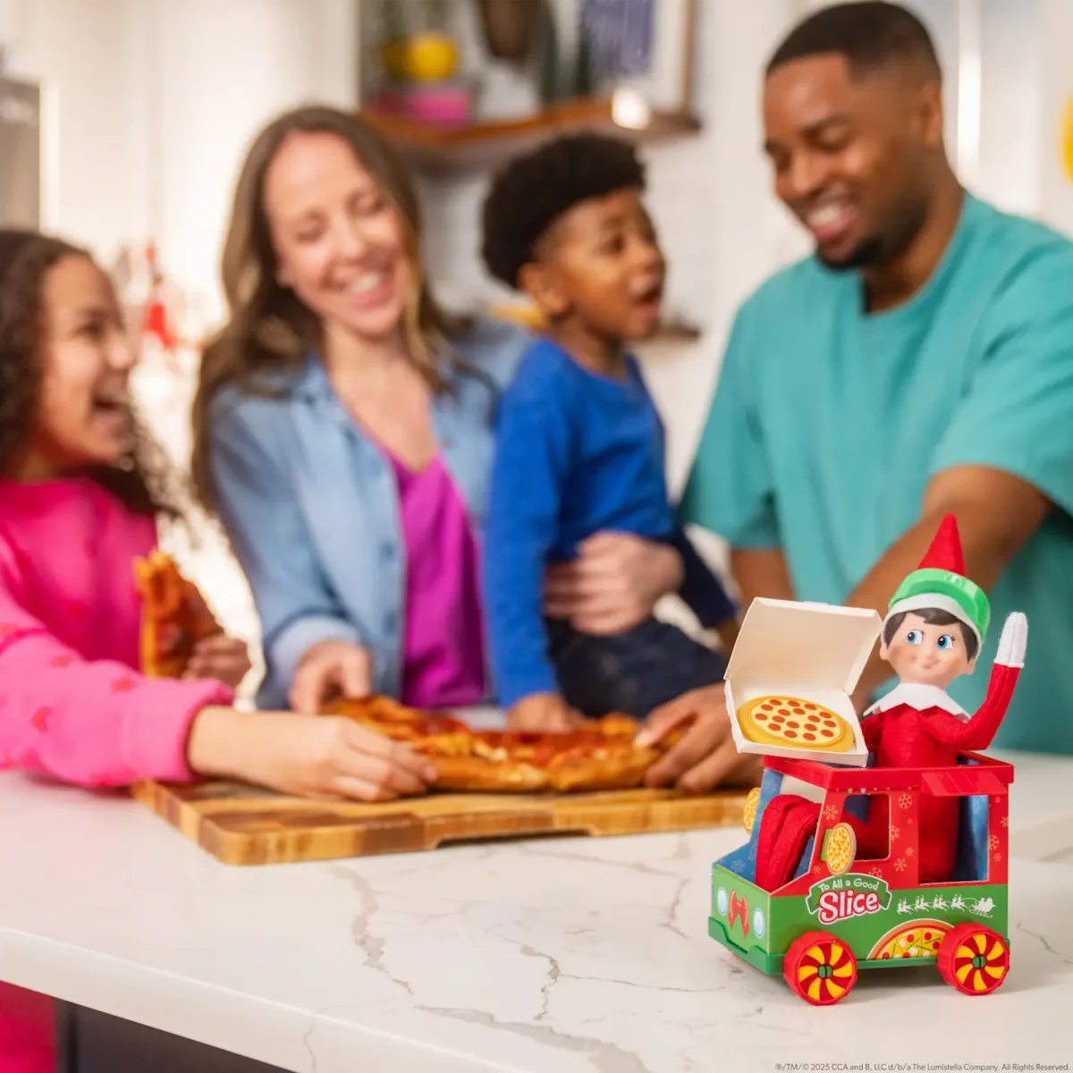 A family enjoys a pizza party with The Elf on the Shelf sitting in the Polar Props Polar Pizza Truck
