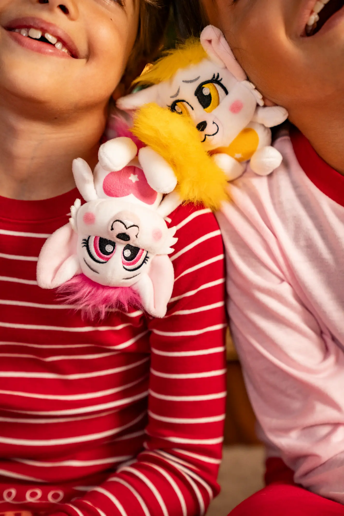 A boy and a girl play with two bogie character plush from The Elf on the Shelf Santaverse