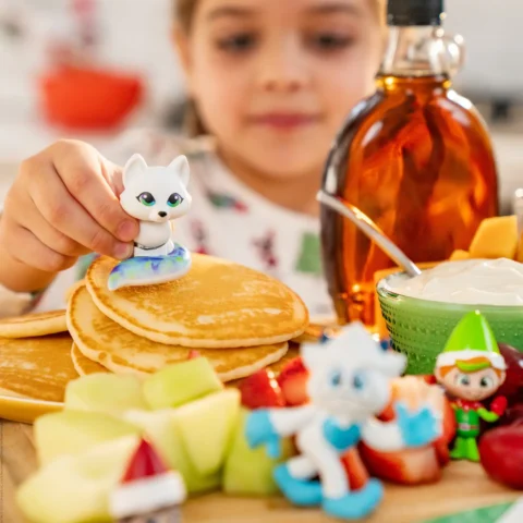 A girl plays with miniature Santaverse toys at the breakfast table