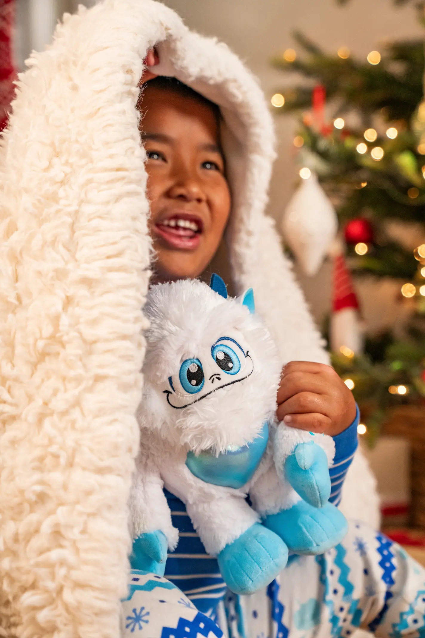 A boy peeks out from a blanket while playing with Little Grunt, the SnoBiggie Yeti