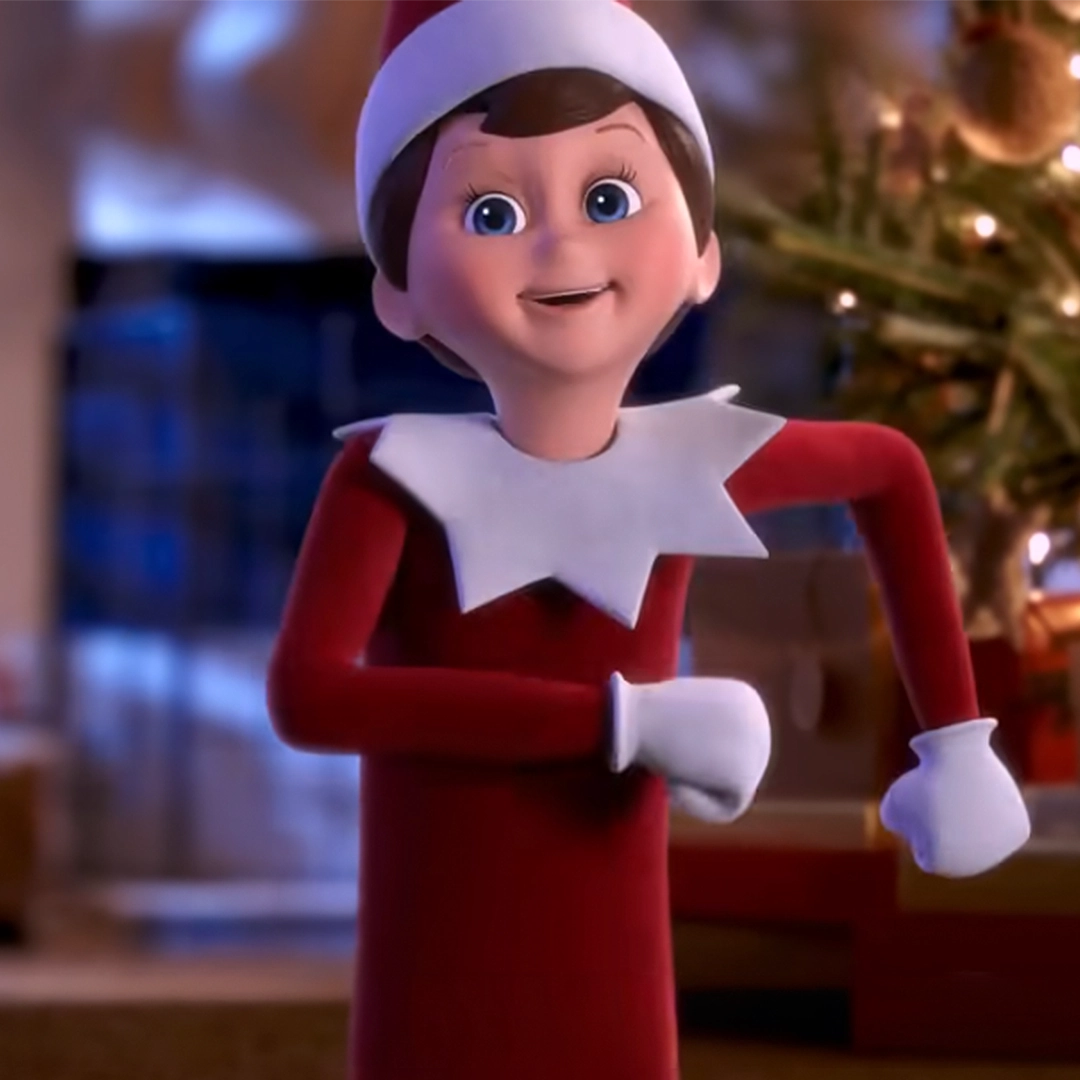 A still of a Scout Elf performing "Scout Elves Don't Rest" from his post at someone's house. You can see a lit Christmas tree in the background. This still is from the sing along version on YouTube.