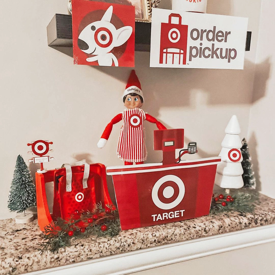 A Scout Elf mans a miniature Target register with the Target dog on a sign overhead, as well as "Order Pickup" sign we are all familiar with from our own Target runs. The scene is staged on a coutnertop or shelf area.