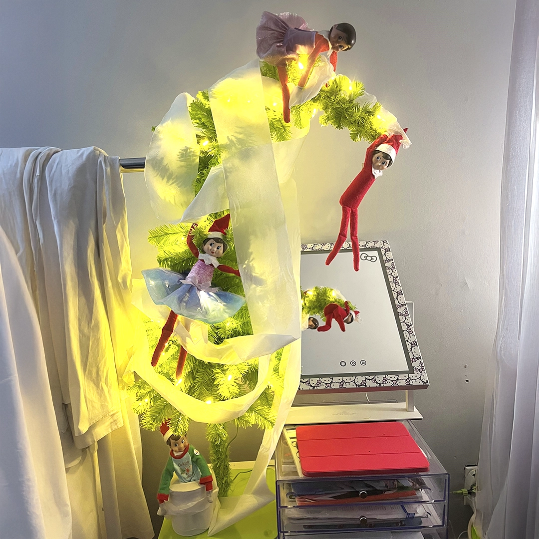 A group of Scout Elves have taken the Christmas tree decorating to an unexpected turn, having wrapped it in toilet paper tinsel! They are seen clinging to the tree in various spots as it tilts from the top