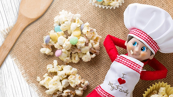 A boy Scout Elf posing beside frosted bunny bite treats on a burlap surface.