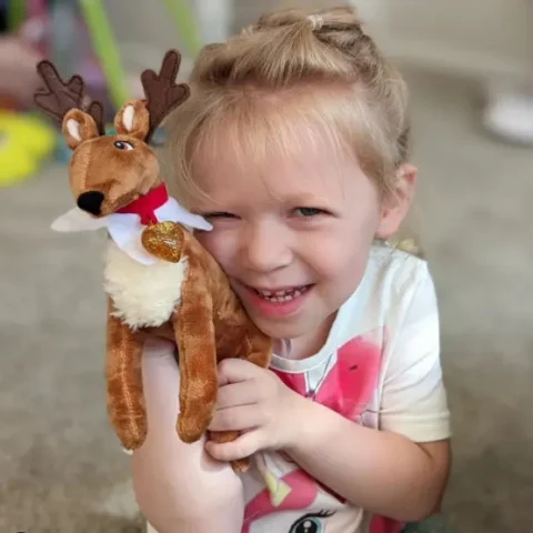 A smiling young girl holds her Elf Pets Reindeer
