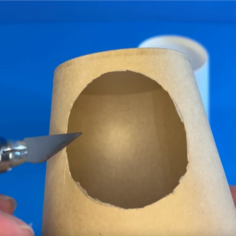 Image shows a paper cup with a hole cut in the side 