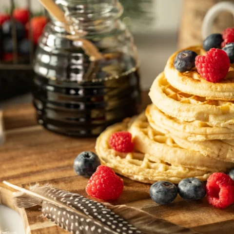 Waffles and berries sit beside a syrup potion and a feather as if a Scout Elf has created a breakfast potion