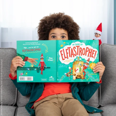 A boy hold In Case of Elftastrophe, a picture book explaining what to do if your Scout Elf loses its magic
