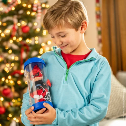 A boy with blond hair holds a Spider-man themed Scout Elf carrier