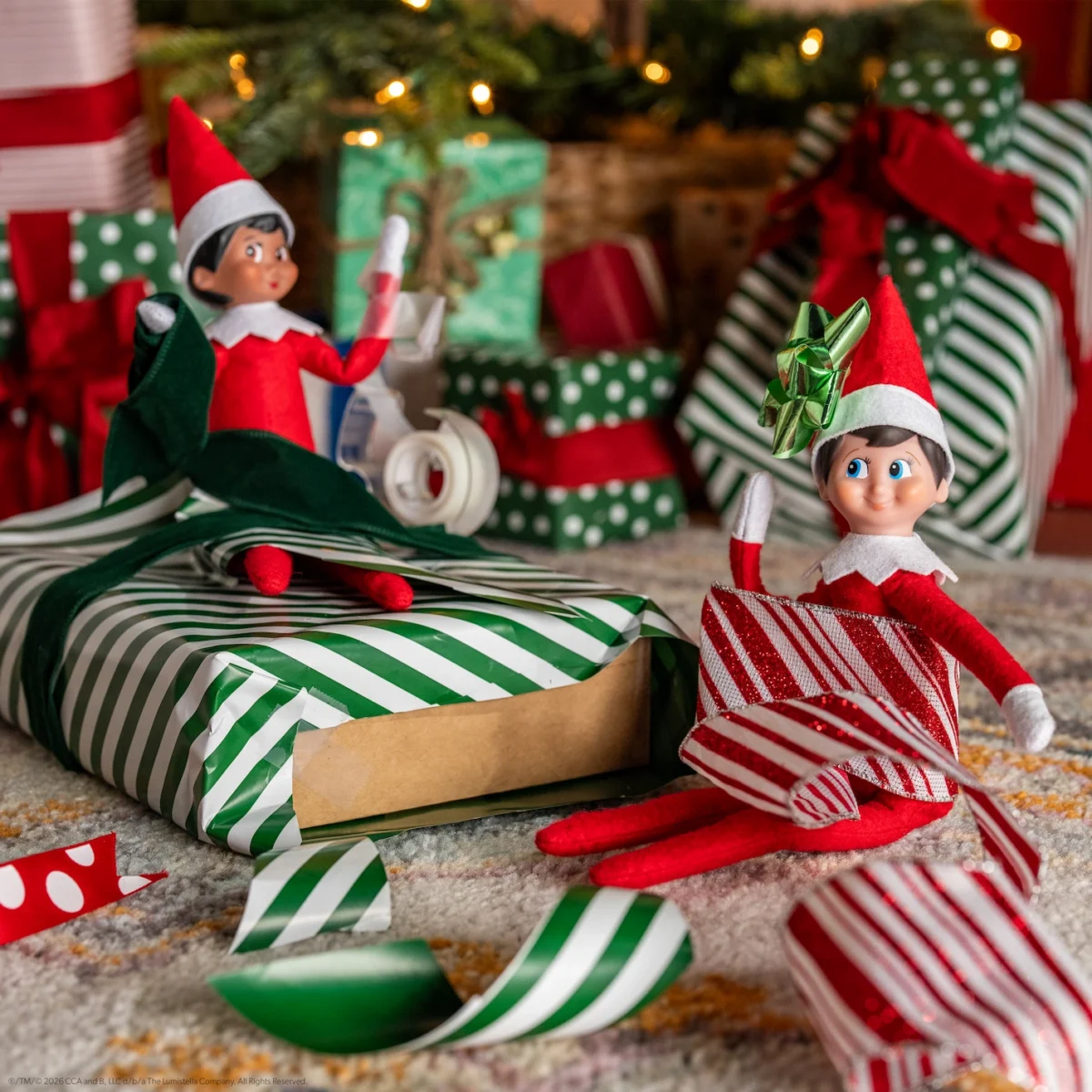 Two elves wrap presents but find themselves stuck in the paper and tape