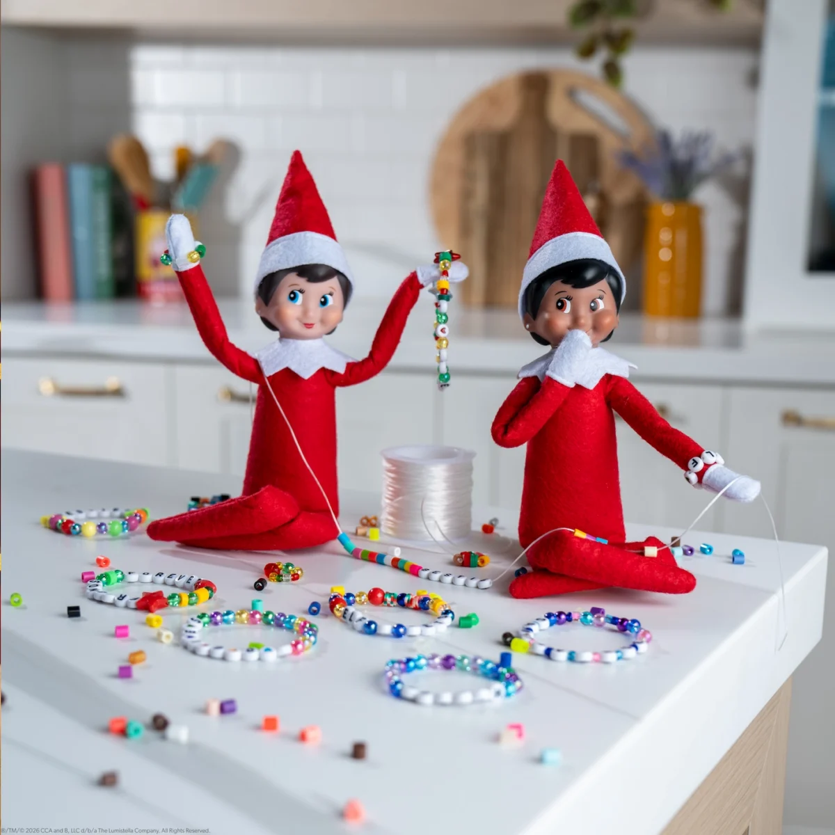 Two Scout Elves sit with a table full of beads making friendship bracelets