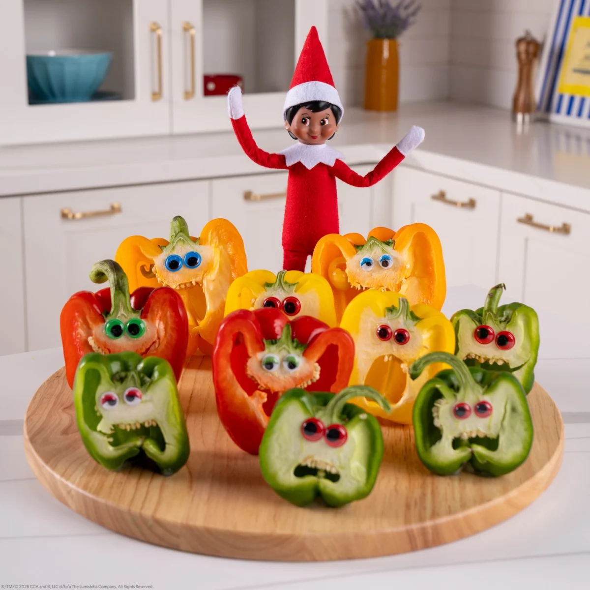A Scout Elf poses with cut peppers with faces made from googly eyes and their cut mouths