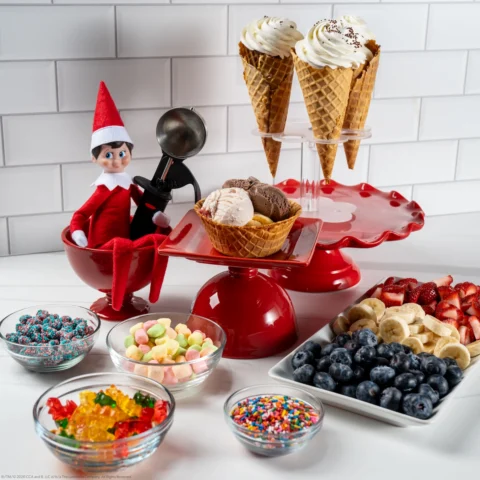 A Scout Elf sits with a spread of fixings for ice cream sundaes