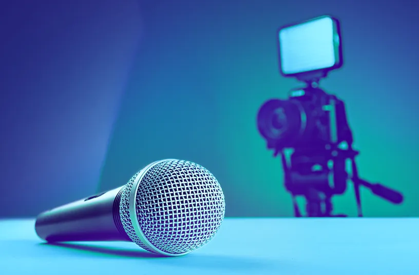 Microphone laid on a table with a camera in the background