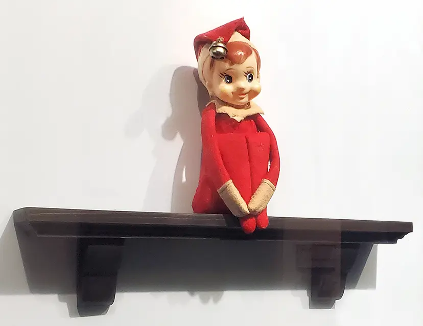 Fisbee, the original childhood elf of the Aebersold family, sitting on a shelf