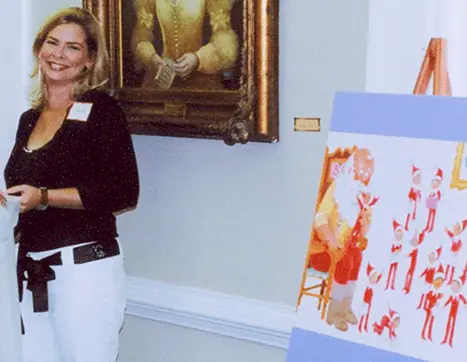 Christa standing next to a poster with The Elf on the Shelf Tradition storybook artwork