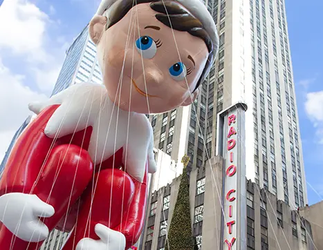 Macy's Thanksgiving Day Parade Scout Elf balloon floating past Radio City Music Hall