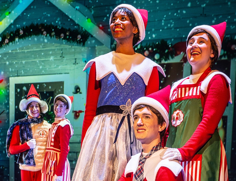 Actors dressed in Scout Elf outfits on a stage during the The Elf on the Shelf musical production