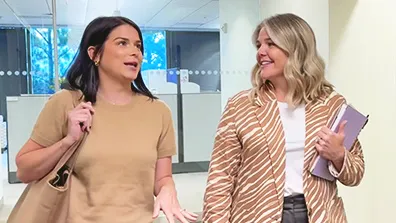 Two women talking as they walk down a hall in the office
