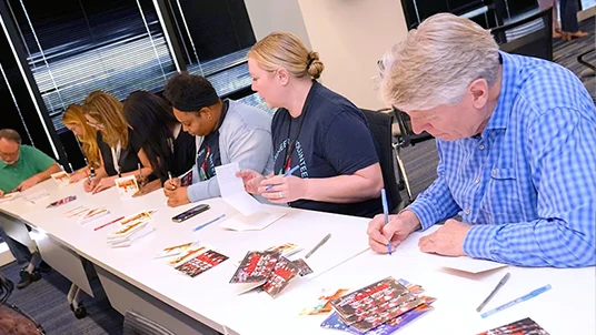 A group of The Lumistella Company employees at a writing on Scout Elf greeting cards