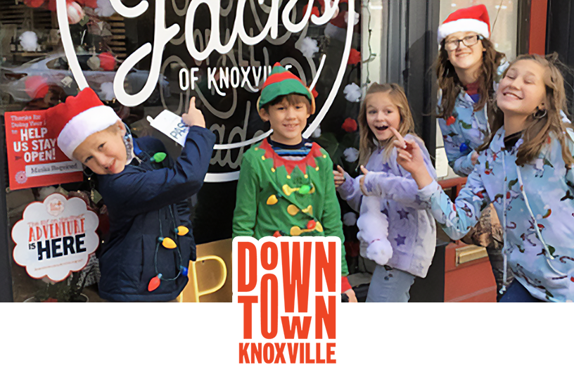 5 children standing in front of a store window that has the The Elf on the Shelf adventure logo on it. The Downtown Knoxville logo overlays the bottom center of the photo.